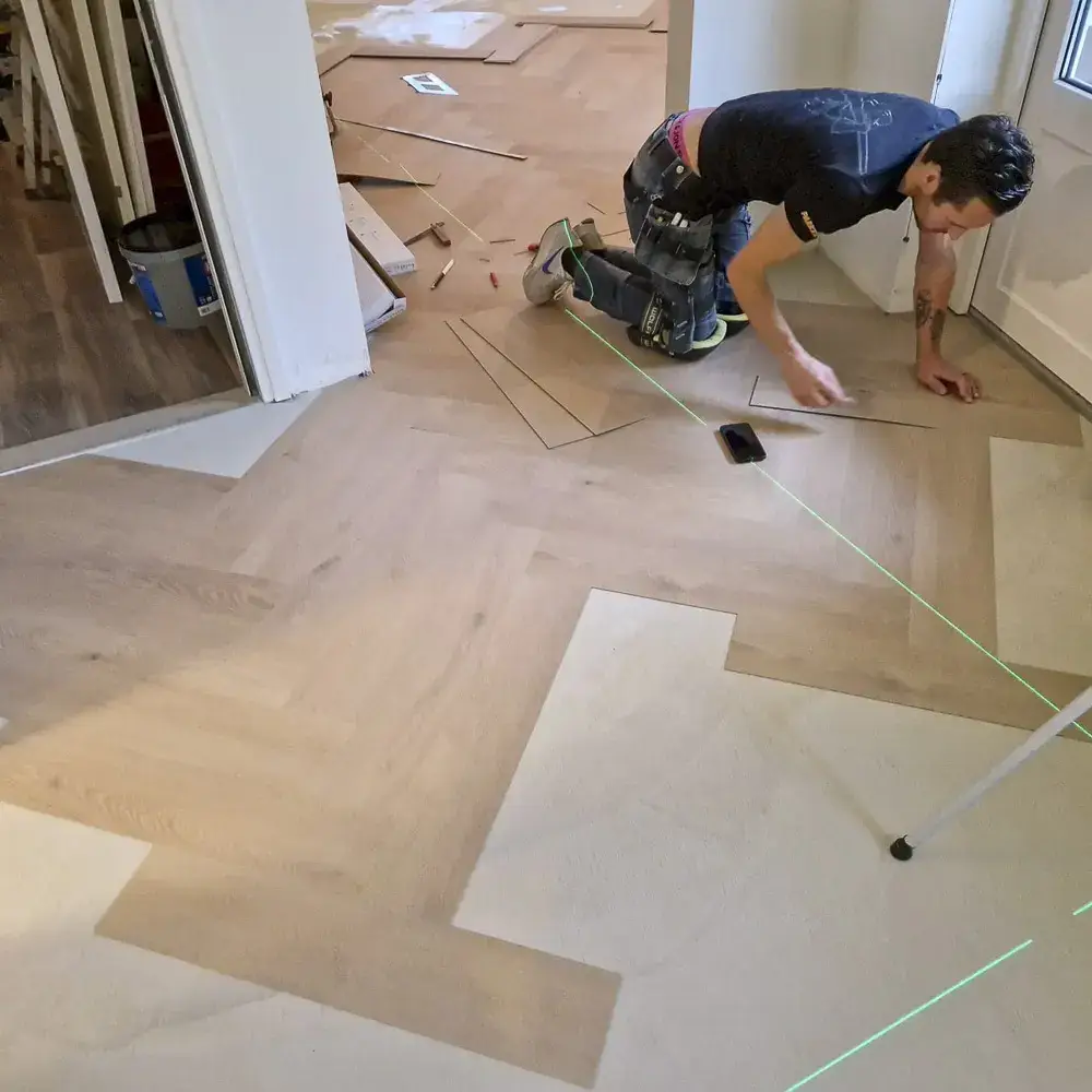 Monteur van Parketreus werkt met laser bij het leggen van een PVC vloer