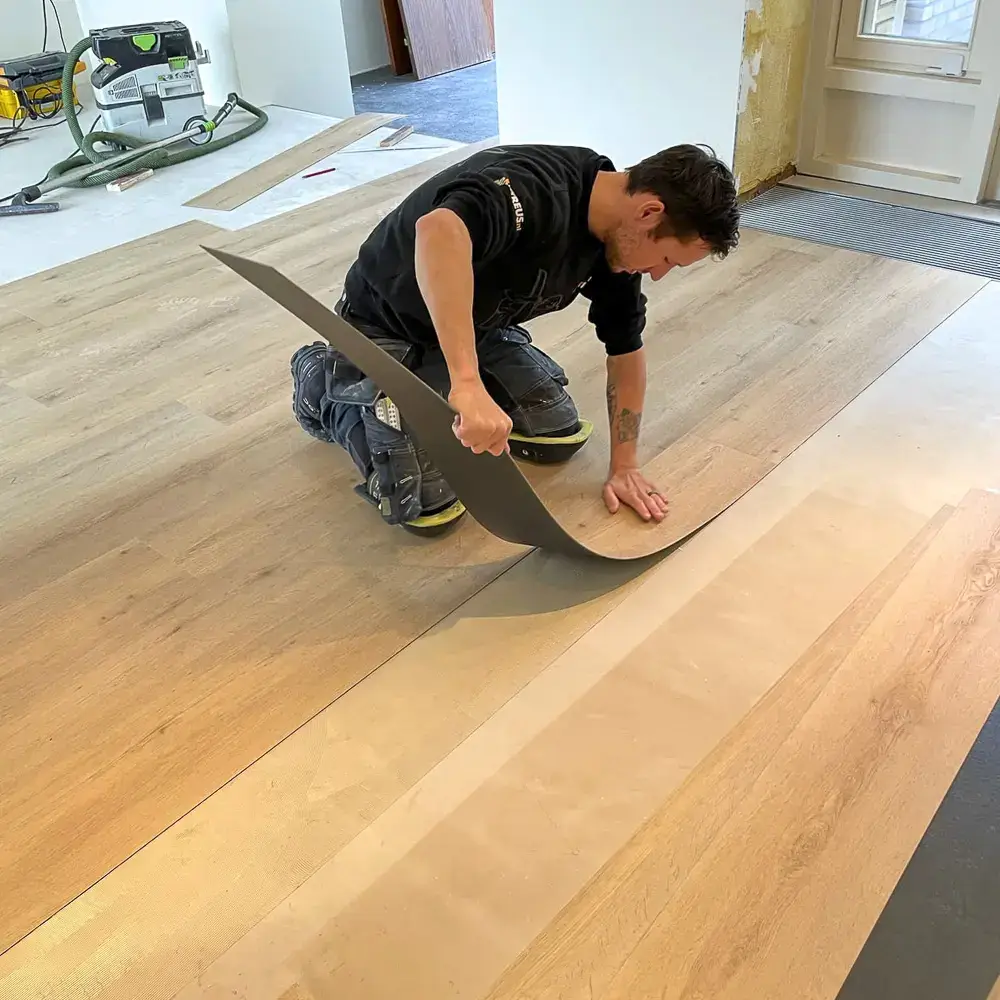 Monteur van Parketreus bezig met het leggen van een PVC vloer.