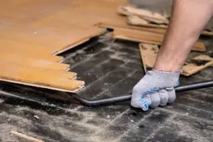 Vakman verwijdert een verlijmde parketvloer met professioneel gereedschap in een woningrenovatie
