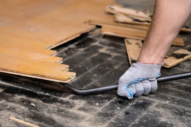 Vakman verwijdert een verlijmde parketvloer met professioneel gereedschap in een woningrenovatie